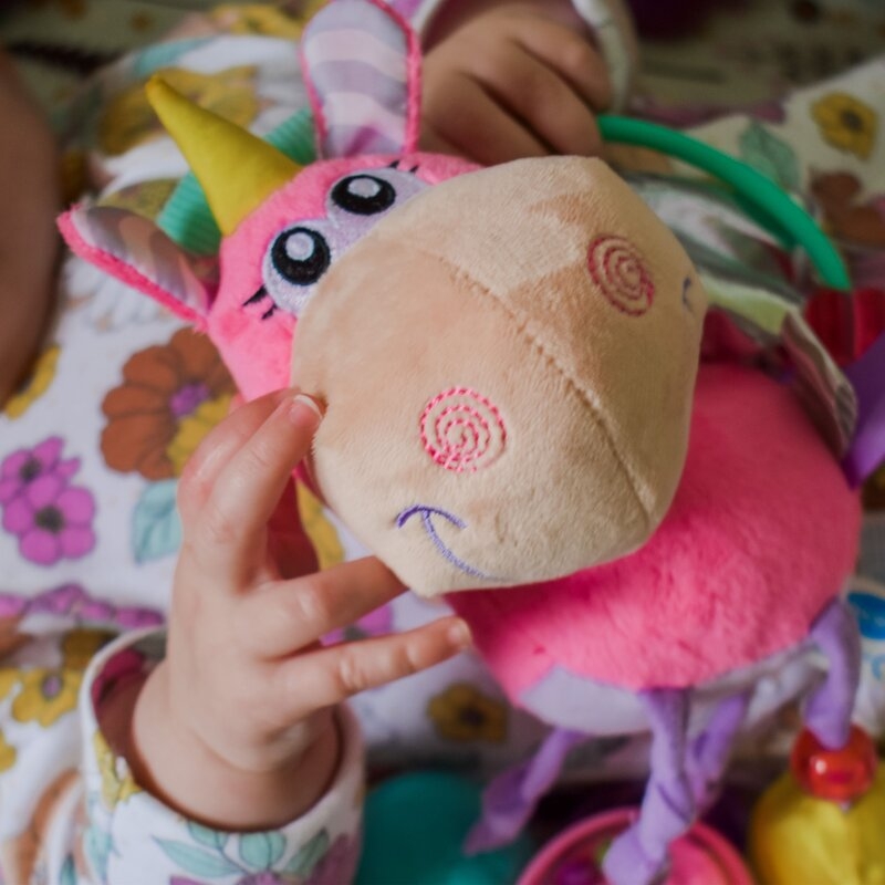 Jucarie din plus, Playgro, Stimuleaza dezvoltarea senzoriala, Utila pentru dentitie, Cu diverse forme si texturi, Cu margele si parti zornaitoare, 0 luni+, Unicorn Activity Rattle